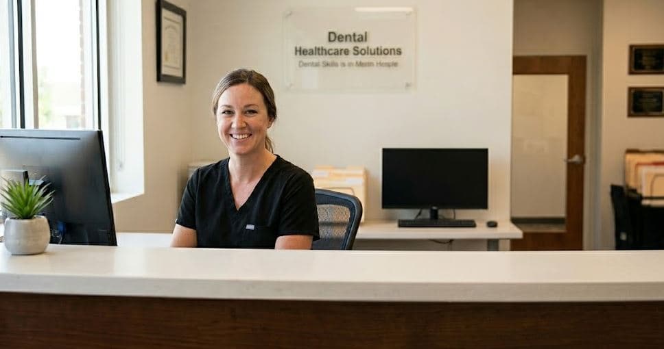 Dental office front desk showing AI software answering phone calls while a human receptionist assists a patient at the desk