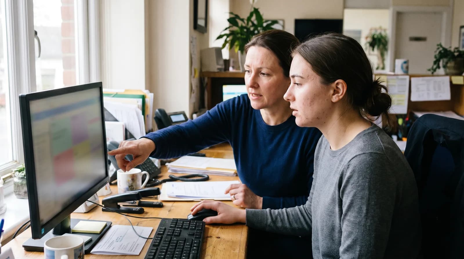 Trainer and new hire at one workstation during dental front desk employee onboarding